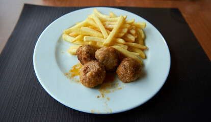 meatballs with chips in white plate on black paper tablecloth
