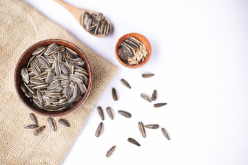Sunflower seeds in wooden bowl and wooden spoon on white table with brown cloth