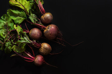 Beetroot on a black background. Red beet with leaves. Healthy food.