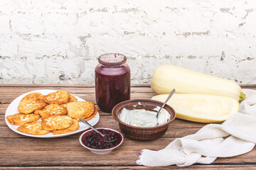 Gluten-free squash pancakes with berry jam. Sour cream. Zucchini. Wooden background.