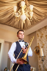 Young groom professional trumpeter holding a trumpet in his hands.