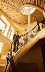 couple of newlyweds are standing on the stairs in a luxurious interior.