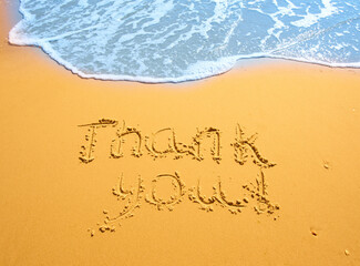 Concept or conceptual hand drawn thank you text carved in a golden sandy beach