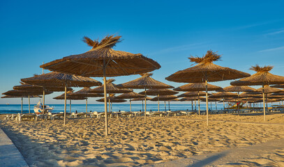 Thatched beach umbrellas and loungers on a beach at an idyllic tropical resort
