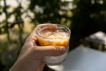 man keep a glass of iced coffee on summer terrace