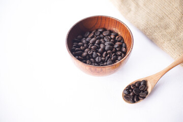 coffee beans in a wooden bowl and wooden spoon on a white table