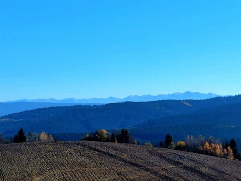 Plowed field with High Tatras background and blue sky in autumn.