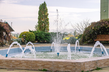A small fountain with small jets of water. Splashes of water and drops from a small fountain.
