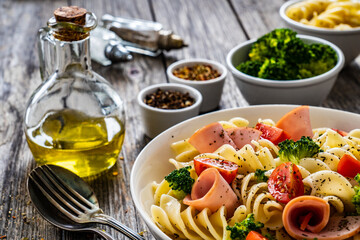 Pasta with ham, broccoli and cherry tomatoes  on wooden table