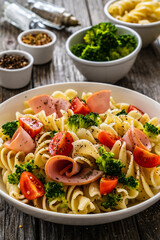 Pasta with ham, broccoli and cherry tomatoes  on wooden table