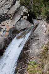 kleiner Wasserfall in bergiger  Landschaft an einem sonnigen Herbsttag