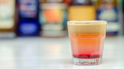 A colorful layered drink shot on a bar prepared by Bartender