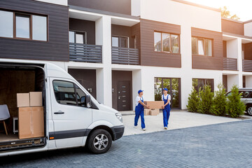 Two removal company workers are loading boxes into a minibus.