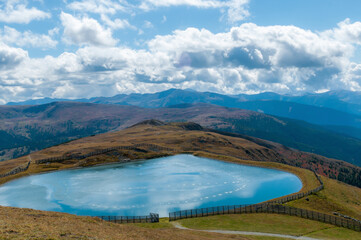 Künstlich angelegter Teich in den Bergen von Österreich. Blick auf die berge und den wolkigen Himmel