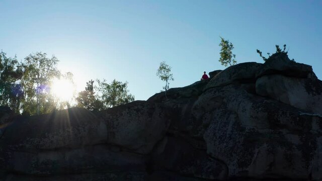 aerial view of a girl doing fitness and yoga on a rock