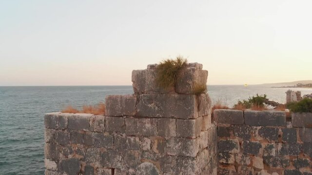 Aerial rising view Antik kiz kalesi fortification walls close-up in Kizkalesi turkish coast in summer
