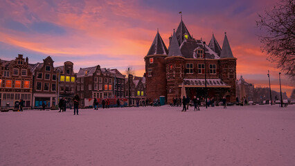 Snowy Nieuwmarkt with the Waag building in the city center from Amsterdam in the Netherlands in winter at sunset