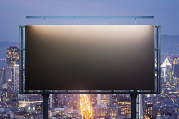 Blank black horizontal billboard on city buildings background at night, front view. Mockup,...