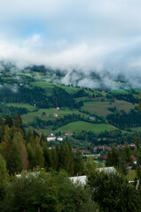 Blick in ein Tal mit sehr tief hängenden Wolken. Blick auf eine kleine Ortschaft in der Steiermark