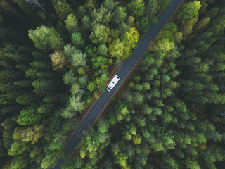 White camper van with solar panels drive through green forest. Aerial top down view. Travel concept. - 475882697