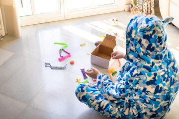 Kid in pajama on floor playing with educational toy at weekend at home