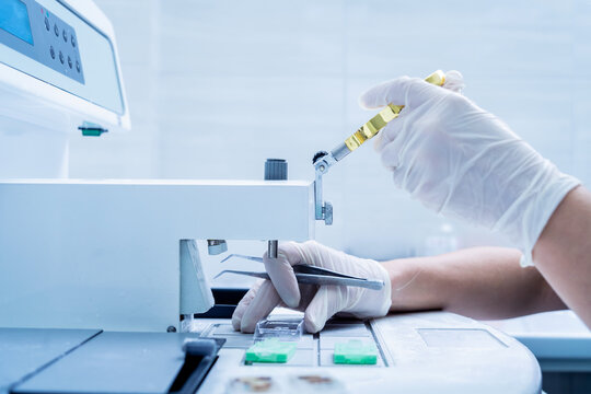 Laboratory assistant works at paraffin wax dispenser tissue embedding machine.