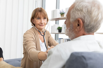 Obraz premium senior woman doctor on home visit and examining elderly man patient by stethoscope