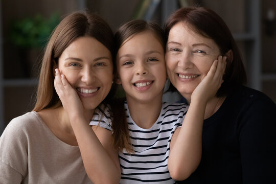 I love you so much mommy and granny. Headshot portrait of affectionate tween girl caress cheeks of beloved retired grandmother young mother. Three generations of women in family cuddle look at camera