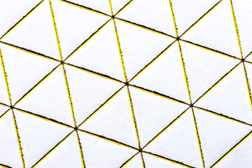 Gold diamond and triangle shaped lines engraved on white paper, top view.