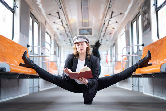 Very flexible woman wearing mask reading book in the subway car sitting in the gymnastic split. Concept of healthy lifestyle and education