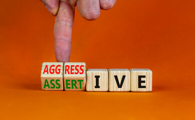 Aggressive or assertive symbol. Businessman turns wooden cubes, changes the word Aggressive to...