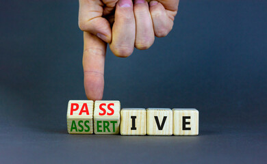 Passive or assertive symbol. Businessman turns wooden cubes and changes the word passive to assertive. Beautiful grey background, copy space. Business, psychological passive assertive concept. - obrazy, fototapety, plakaty