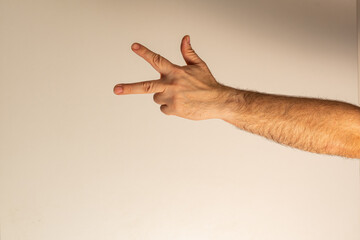 A finger gesture showing the number three. The thumb, index finger and middle finger are protruding, the rest are pressed against the palm.