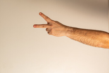 A man's hand showing a gesture signifying victory, peace. The index and middle fingers are...