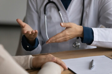 Doc consulting patient. Close up of young lady doctor in white coat talk to female patient explain...