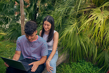 young couple looking a laptop and talking with her friends