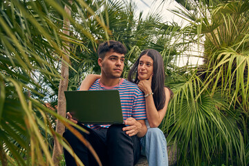 young couple looking a laptop and talking with her friends