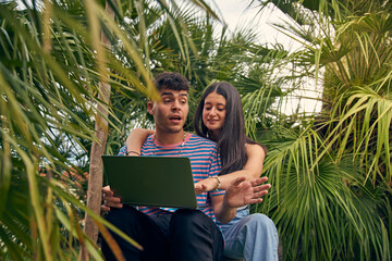 young couple looking a laptop and talking with her friends