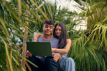 young couple looking a laptop and talking with her friends