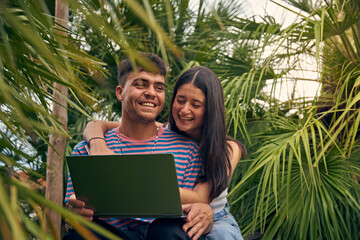 young couple looking a laptop and talking with her friends