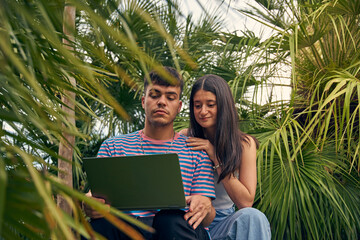 young couple looking a laptop and talking with her friends