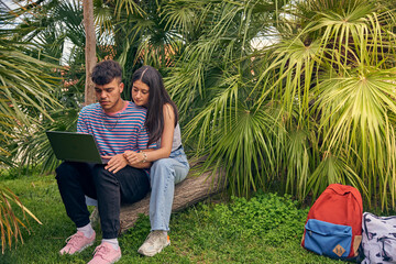 young couple looking a laptop and talking with her friends