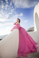 Romantic beautiful bride in amazing dress posing on terrace with sea and mountains in background.
