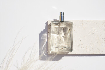 Transparent bottle of perfume on stone plate on a white background. Fragrance presentation with...