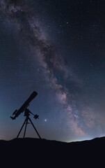 Silhouette of a telescope against the background of the Milky Way. The telescope is a refractor and...