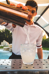 Vertical shot of a Caucasian bartender making cocktails at the venue of a fancy pool party