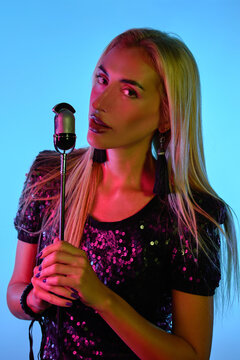 Young sexy blonde female singer holding a microphone