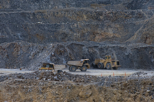 Very large excavators and dump trucks at work in a deep quarry