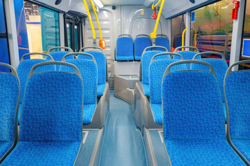 interior of bus. Concept - municipal transport. Seats on city bus or tram. And public transport equipment. Empty bus with blue seats. Public transport with yellow handrails. Trolleybus inside view
