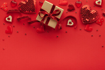 Festive composition with gift box and hearts on red background. Top view, copy space. Valentine's day concept.